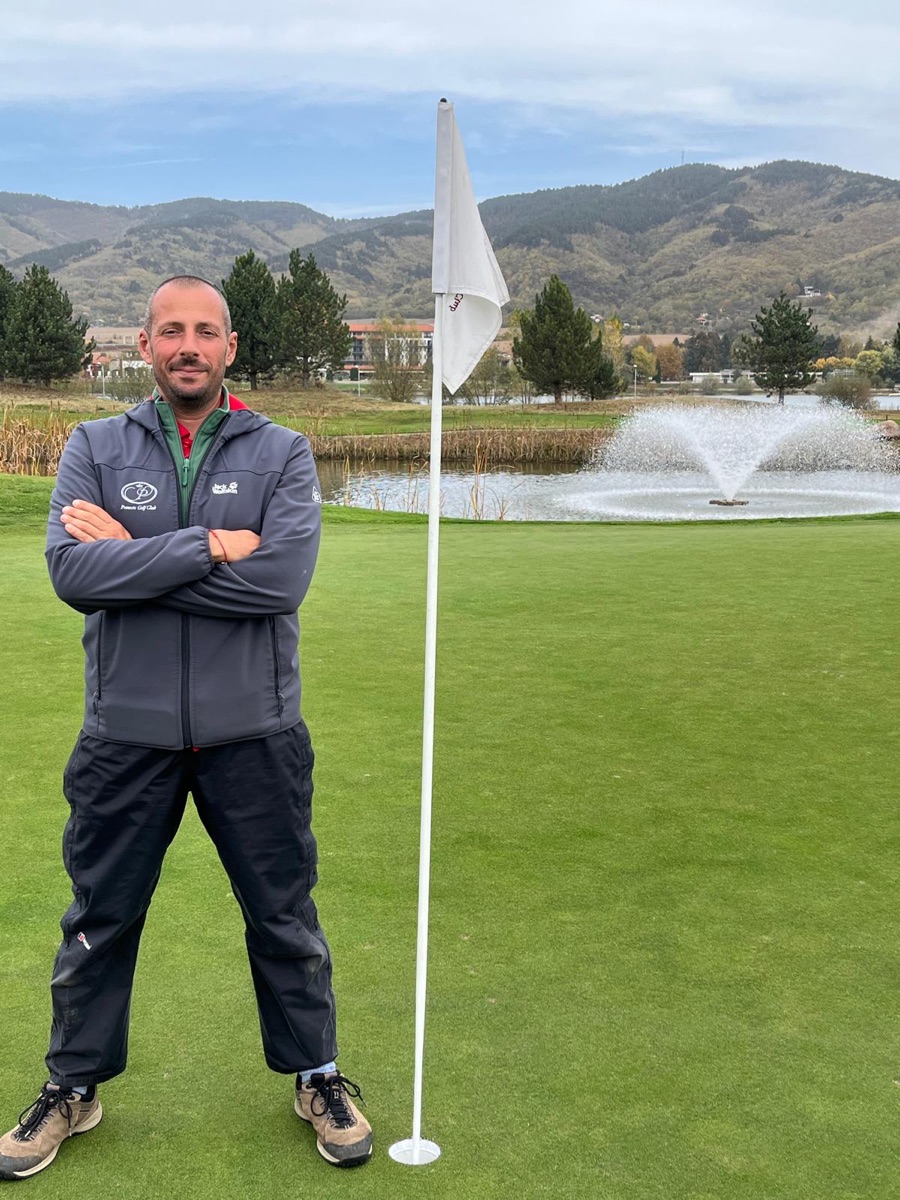 Yavor standing by the flag with the lake fountain behind